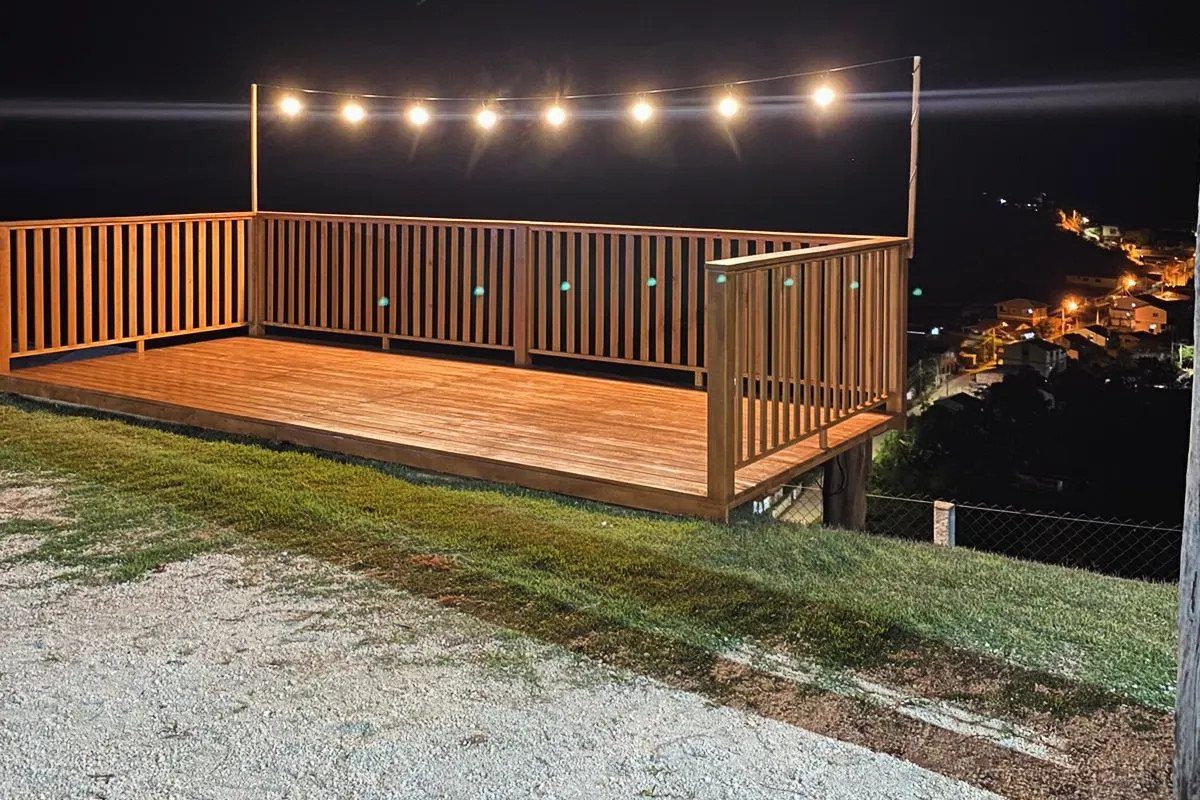 Wooden deck at night featuring a string of glowing warm light bulbs hanging overhead.