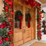 Wooden double doors decorated with festive evergreen garlands, red ornaments, and large red bows.