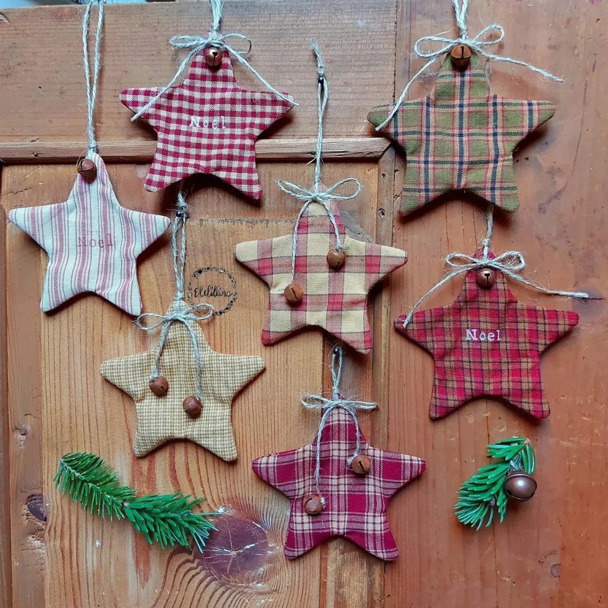 Seven fabric star ornaments with plaid patterns hanging on a rustic wooden background.